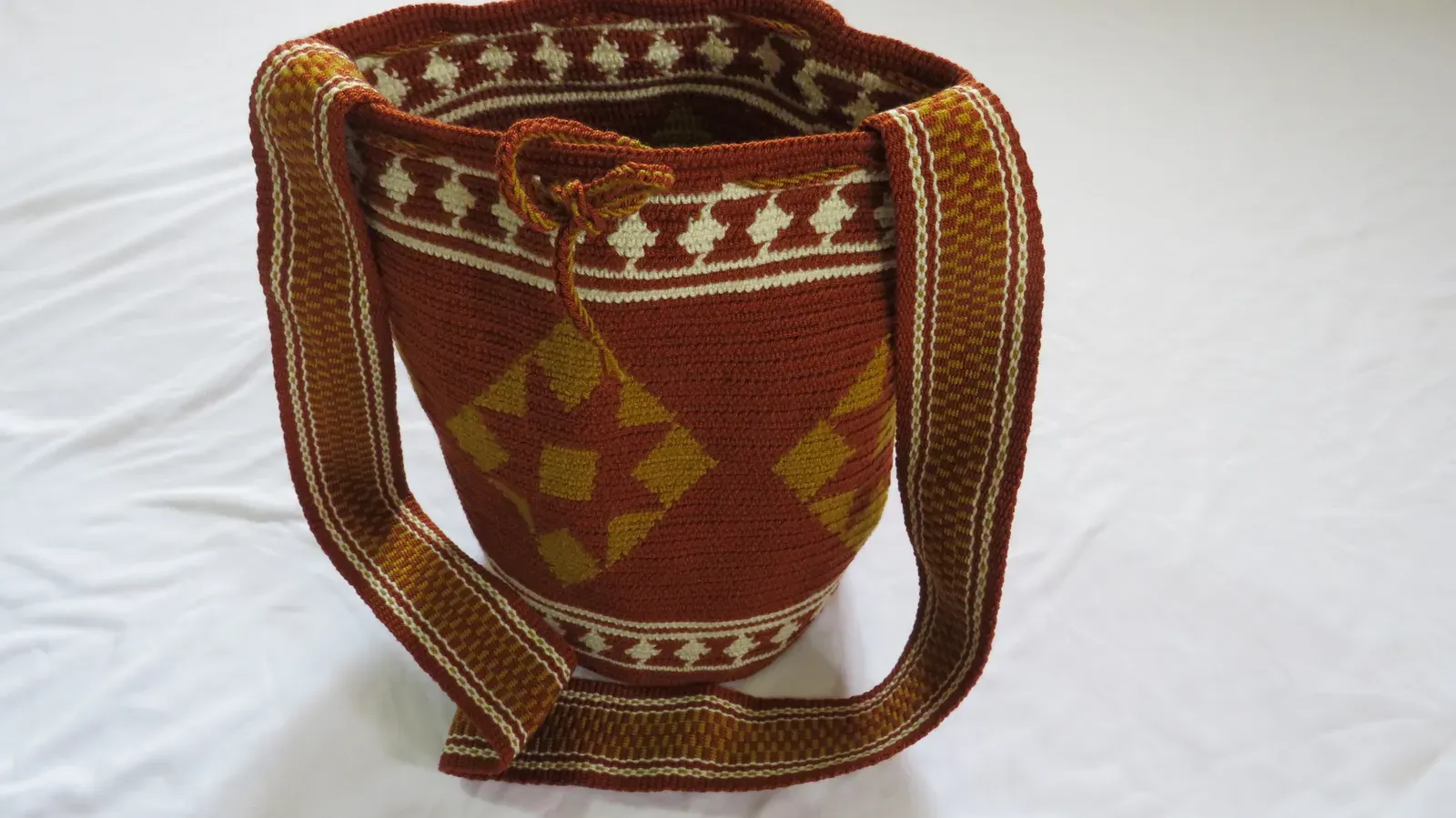 Mochila terracota con rombos y figuras en hilo crudo